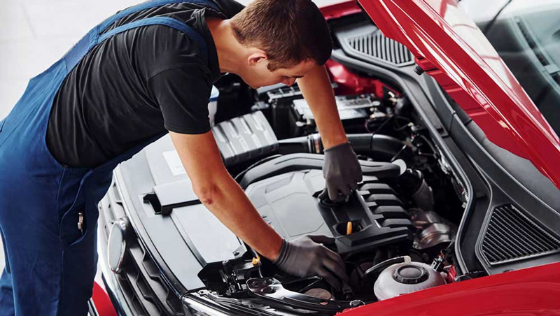 Mechanic under the hood of car repairing it